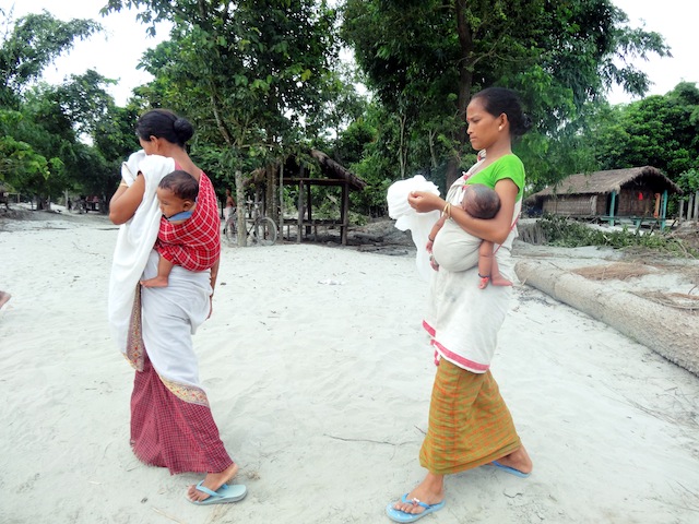 Women from Rekhasapori village in Dhemaji district walk on the hot sand towards a health camp set up by Save The Children. Most people complain of rashes, and acidity from acute hunger. Credit: Priyanka Borpujari/IPS