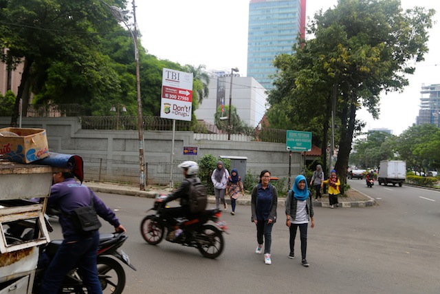 A street food vendor walks past a sign, warning residents against taking drugs, outside of the Russian consulate in South Jakarta. Indonesia imposes harsh penalties, including capital punishment, for drug-related crimes. Credit: Sandra Siagian/IPS