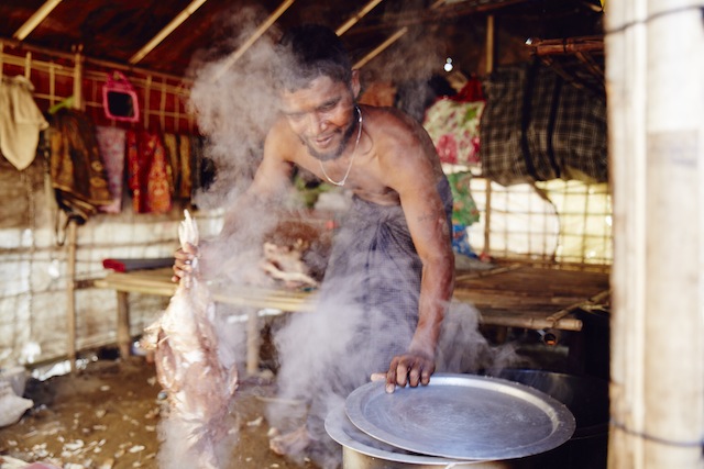 Angu Mia plucks and boils chickens for a female Rakhine business owner, who pays him 0.4 dollars per bird and then sells the meat at a local market. Credit: Courtesy Rob Jarvis