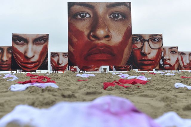 The Rio Peace organisation covered the sand on Copacabana beach, in the city of Rio de Janeiro, with blood-red or bloody women's underwear and giant photos of women's faces, also bloodied, representing the women who have been murdered in Brazil. Credit: Tânia Rêgo/Agência Brasil