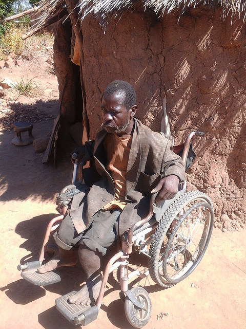 Moses Kasoka sits in his wheelchair outside his grass-thatched hut in Pemba, Zambia. Credit: Friday Phiri/IPS