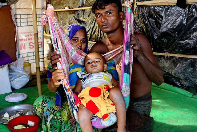 A Rohingya couple, Mohammad Faisal and his wife Hajera, pose for a photo with their child at their camp at Teknaf Nature's Park, Bangladesh. Credit: Farid Ahmed/IPS