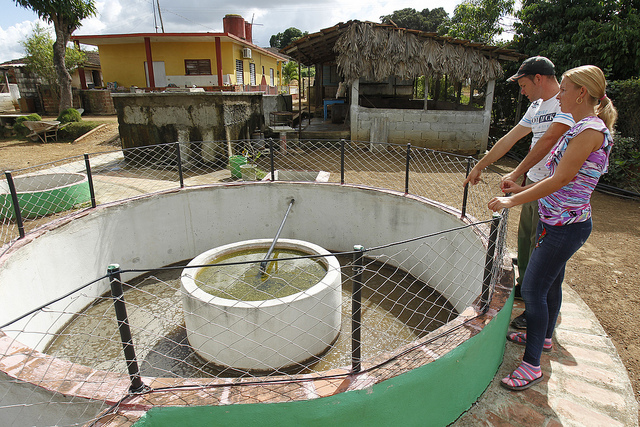 Farmer Yuniel Pons and his wife Sandra Díaz stand next to the biodigester installed by their house, which with its innovative system supplies energy to the kitchens of eight homes in La Macuca, a rural settlement in the municipality of Cabaiguán, in central Cuba. Credit: Jorge Luis Baños/IPS