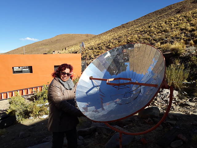 Celia Vilte, a teacher in San Francisco, stands next to one of the two solar cookers located in the center of town, where families place pots to boil water using renewable energy. The high plateaus of the Puna, an ecosystem that Argentina shares with Chile, Bolivia and Peru, have excellent solar radiation conditions. Credit: Daniel Gutman/IPS