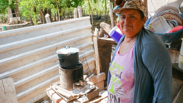 Petrona Cañénguez shows how she cooks bean soup on an energy-efficient rocket stove in an outside room of her home in the hamlet of San Sebastián El Chingo, one of the beneficiaries of a sustainable development programme in the municipality of San Luis La Herradura, on El Salvador's southern coast. CREDIT: Edgardo Ayala /IPS