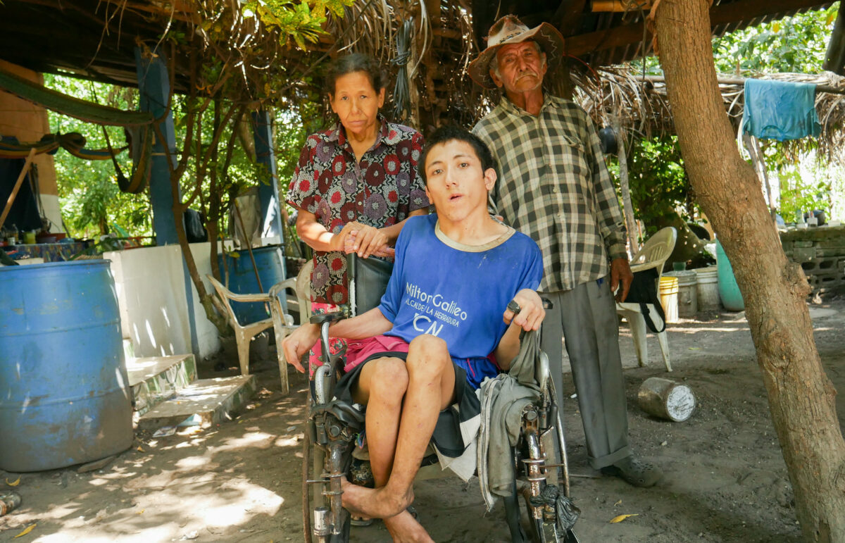 Francisco Martínez, 77, with his wife Gloria García, 50, and their severely disabled 21-year-old son Fredy Martínez pose for a photo in the courtyard of their house in Cuatro Vientos, a settlement formed some 20 years ago by homeless families from various parts of El Salvador. The Martínez family fears that they will be evicted because the property is claimed by one of the country’s main banks. CREDIT: Edgardo Ayala/IPS