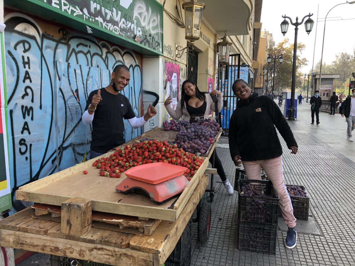 Venezuelan immigrants Engelin, Jorgelis and Edgar sell fruit at a street stall on Alameda Avenue, near the La Moneda presidential palace in Santiago, Chile. CREDIT: Orlando Milesi/IPS