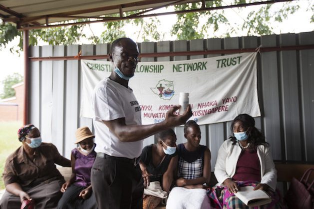 Reki Jimu (51) has lived with HIV for nearly two decades. Here he shows a container of antiretroviral drugs to HIV/AIDS support group members at Chitungwiza government hospital outside Harare, the Zimbabwean capital. Credit: Jeffrey Moyo/IPS.