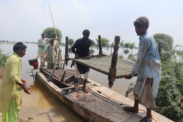 Boaters carry woven rope beds from flooded villages to dry land.  Credit: Altaf Hussain Jamali / IPS