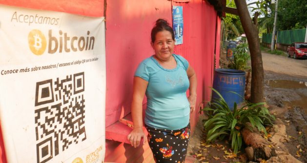 María del Carmen Aguirre, 52, stands outside her home and pizza business in El Zonte, on the Pacific coast of El Salvador. Her daughters send her remittances from the United States, but they use traditional systems and not the bitcoin electronic wallet, after this country became the first to make bitcoins legal tender on Sept. 7, 2021. CREDIT: Edgardo Ayala/IPS