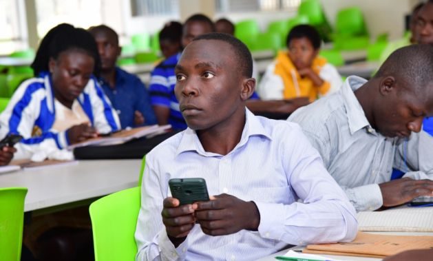 Ugandan Teachers Go Digital - A student teacher at National Teacher's College Kabale follows a lecture through his smartphone. Credit: Michael Wambi/IPS.