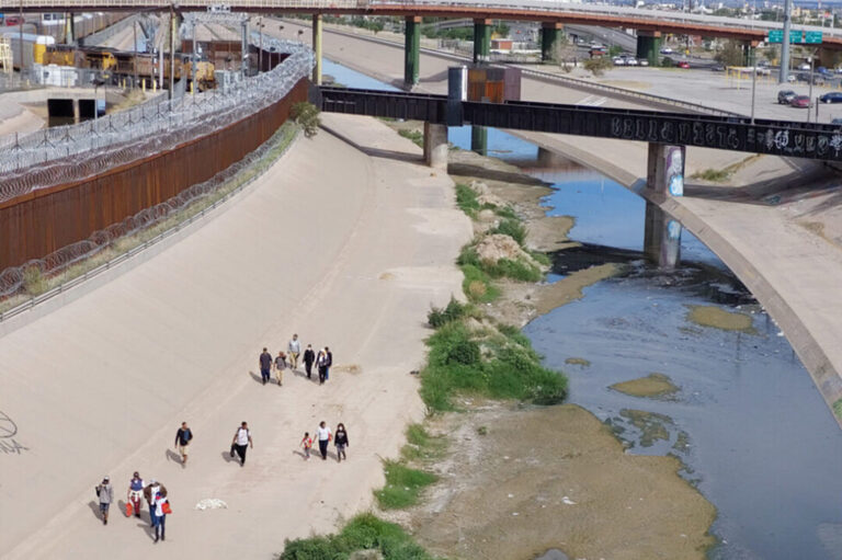Venezuelan migrants walk in Mexico's Ciudad Juarez between the Rio Grande and the wall that separates them from the United States, a border that they will no longer be able to cross on foot but only by air and with express permission from Washington. CREDIT: Rey R. Jáuregui/Pie de Página