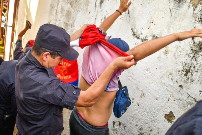 A police officer stops a young man in San Salvador and checks his back and other parts of his body for gang-related tattoos, one of the elements used by authorities to track down gang members in El Salvador. Since the state of emergency was declared, 58,000 people have been detained, in many cases arbitrarily, among them members of the LGBTI community. CREDIT: National Civil Police