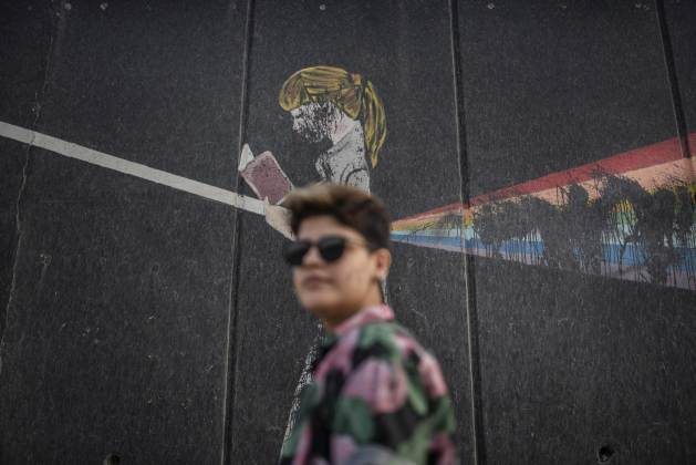 Varin, 23, poses next to a gay rights mural in Sulaymaniyah.  It wasn't long before it was vandalized.  Credit Andoni Lubaki/IPS - Campaign to harass members of the LGBTI community in Iraq condemns much of a life of isolation to avoid arrest, torture and murder