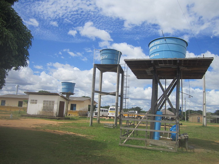 Een foto van de drie watertanks in het dorp Darora, waarvan er één water bevat dat drinkbaar is gemaakt door chemische behandeling.  Het grootste en langste gebouw is de middelbare school die de Macuxi-inheemse gemeenschap bedient die in Roraima, in het noorden van Brazilië, woont.  CREDIT: Mario Osava/IPS