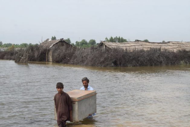 A father and son remove their belonging from their flooded home in Taluka, Shujabad, District Mirpurkhas. Credit: RDF