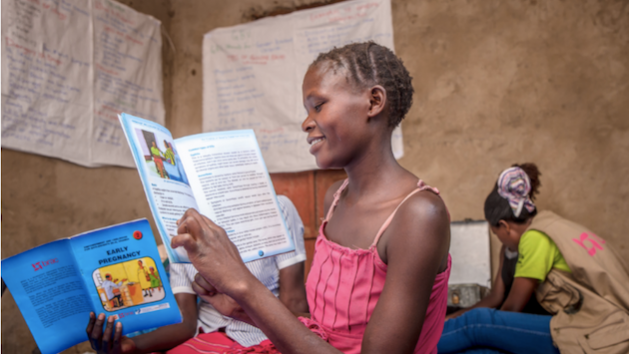 A girl reads a story book with lessons on life skills at an ELA club in Uganda. Credit: Uganda/BRAC