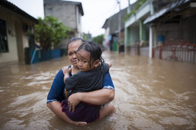 Woman and child walk through flood waters in east Jakarta, Indonesia. Climate change impacts are becoming more severe, and there is concern that vulnerable developing countries will not receive the assistance required to mitigate risks. Credit: Kompas/Hendra A Setyawan / World Meteorological Organization