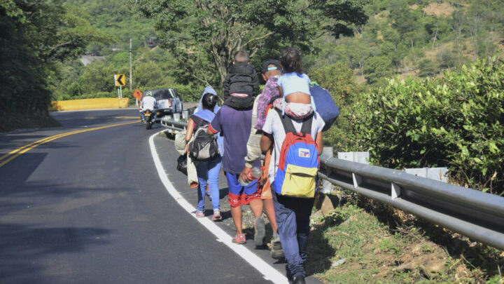 The backpack decorated with the tricolor Venezuelan flag, which is given to primary school students in the country’s public schools, is often carried by immigrants, such as these walking along a Colombian highway, as many students and teachers, in addition to dropping out of school, go abroad. CREDIT: JRS