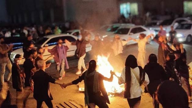 Several women dance and burn their veils during a nighttime demonstration in Bandar Abbas, southwestern Iran. The protest is in response to the tragic deaths of Jina Amini, who was beaten for not wearing the veil properly, and Armita Geravand on October 28 for similar reasons. Credit: Social networks