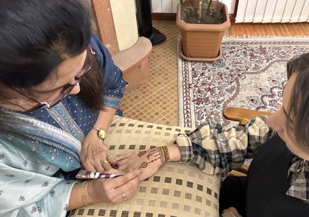 Deepali Shah paints mehendi on a girl's hand. What was once a hobby has become a source of income for her. Credit: Lilit Gasparyan/IPS